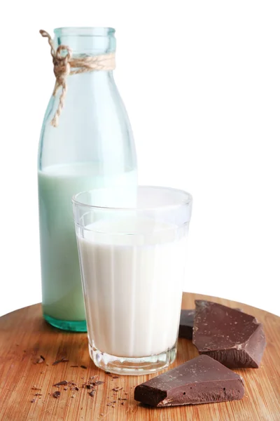 Bicchiere e bottiglia di latte con pezzi di cioccolato su tagliere di legno isolato su bianco — Foto Stock