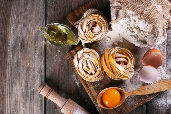 Rohe hausgemachte Pasta und Zutaten für Pasta auf Holzgrund — Stockfoto