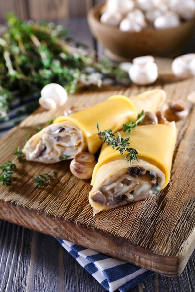 Pfannkuchen mit cremigen Pilzen auf Holzschneidebrett, Nahaufnahme — Stockfoto