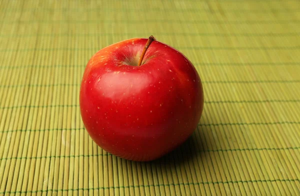 Äpple på färgbakgrund bambu matta — Stockfoto