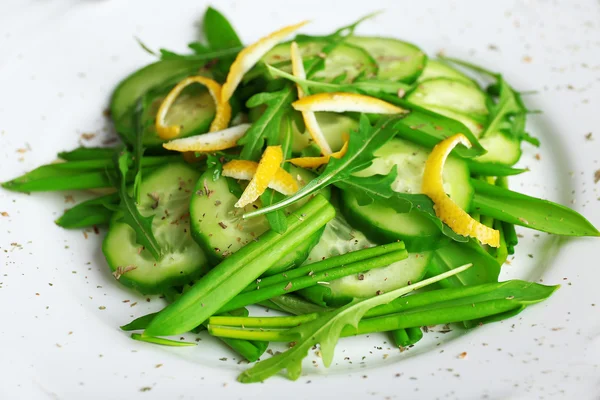 Ensalada verde con pepino, rúcula y cáscara de limón en plato, primer plano —  Fotos de Stock