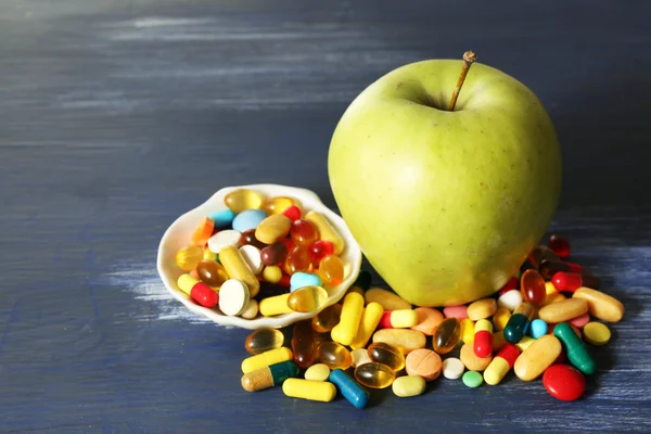 Manzana y píldoras de colores, sobre fondo de madera de color —  Fotos de Stock