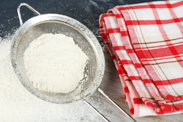 Sifting flour through sieve on wooden table, closeup — Stock Photo, Image