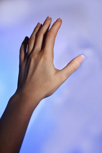 Main féminine et ombre bleue sur fond coloré clair — Photo