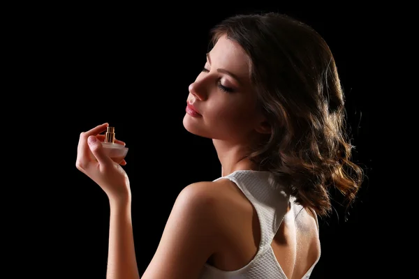 Hermosa mujer con frasco de perfume sobre fondo negro —  Fotos de Stock