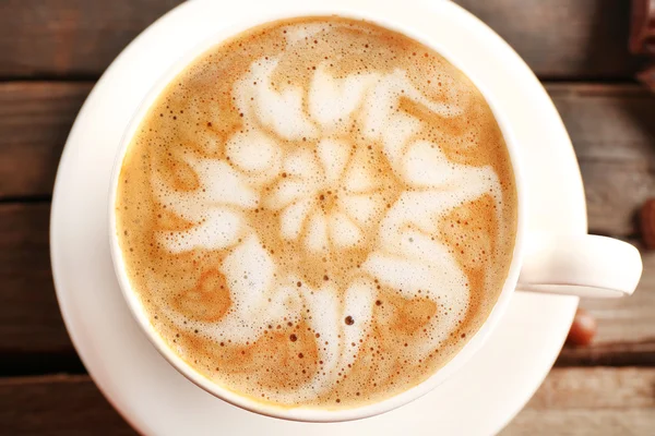 Kopp kaffe latte art på träbord, ovanifrån — Stockfoto