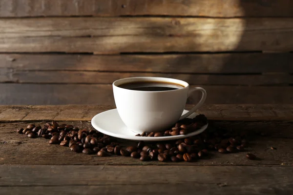 Xícara de café com grãos em fundo de madeira — Fotografia de Stock