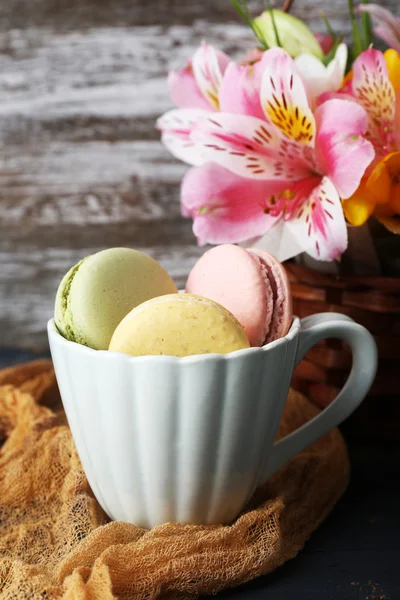 Macaroon delicioso com belas flores em fundo de madeira — Fotografia de Stock