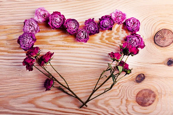 Corazón de flores secas sobre fondo de madera — Foto de Stock