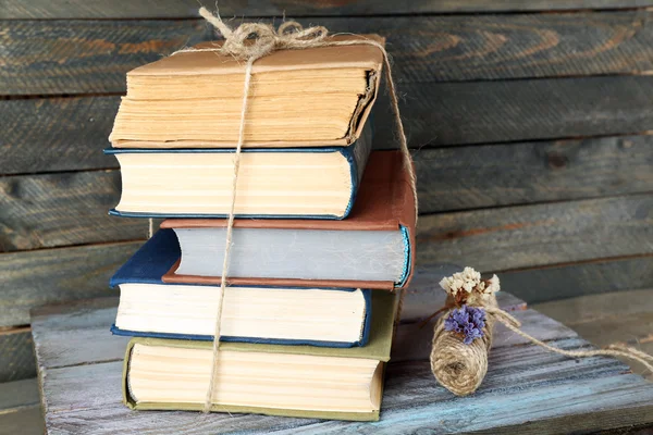 Stack of books with dry flowers on wooden background — Stock Photo, Image