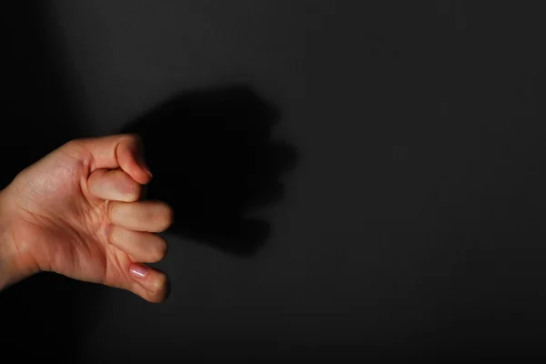 Sombra de mano femenina formando rostro humano sobre fondo oscuro —  Fotos de Stock