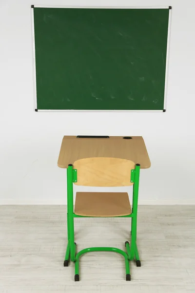 Quadro negro e mesa de madeira com cadeira na sala de aula — Fotografia de Stock