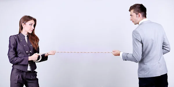 Gente de negocios estirando la cuerda sobre fondo gris — Foto de Stock
