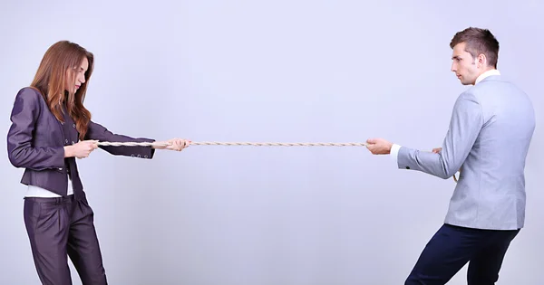 Empresários esticando corda no fundo cinza — Fotografia de Stock