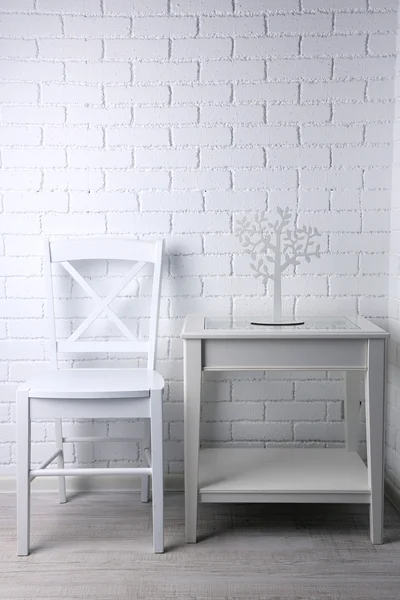 Chair and nightstand on white brick wall background — Stock Photo, Image