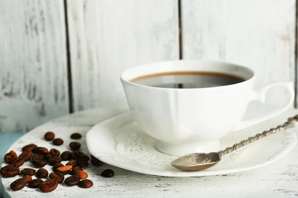 Šálek kávy s fazolemi na barvy rustikální dřevěné pozadí — Stock fotografie
