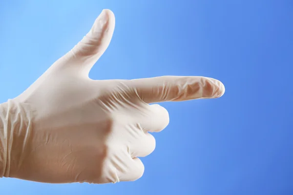 Main de médecin en gants stériles sur fond bleu — Photo