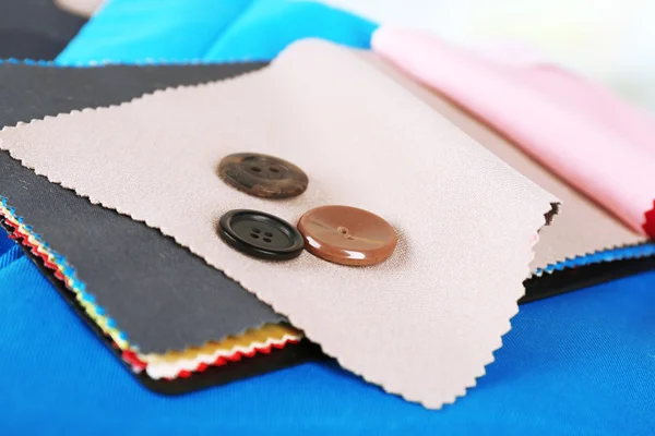 Colorful fabric samples and buttons on light blurred background — Stock Photo, Image