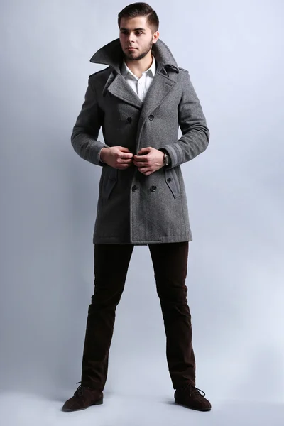 Young man in coat on gray background — Stock Photo, Image