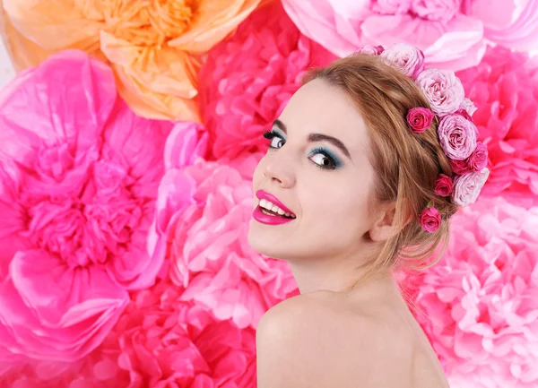 Portrait of young woman with flowers in hair on bright pink background — Stock Photo, Image