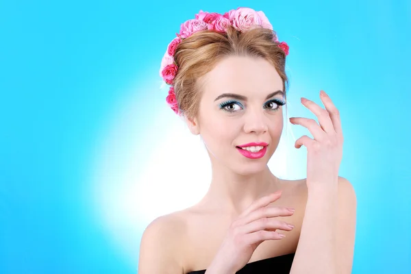 Retrato de mujer joven con flores en pelo sobre fondo azul —  Fotos de Stock