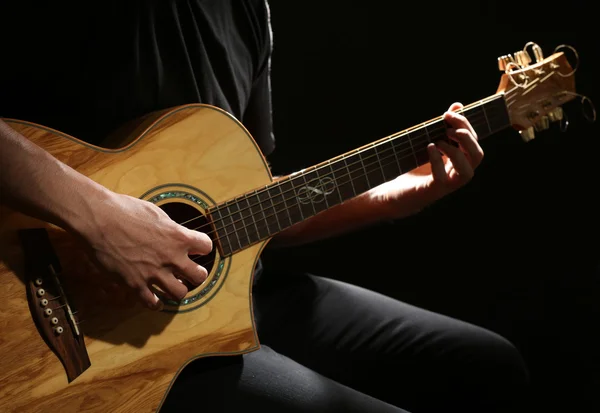 Fiatal férfi játszik akusztikus gitár sötét háttér — Stock Fotó