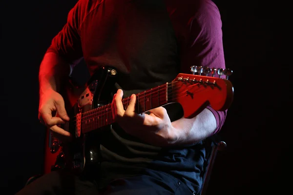 Jovem tocando guitarra elétrica no fundo escuro — Fotografia de Stock