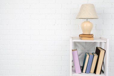 Kitap ve tuğla duvar arka lamba ile ahşap raf