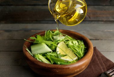 Ahşap masa, closeup Zeytinyağlı yeşil salata poring