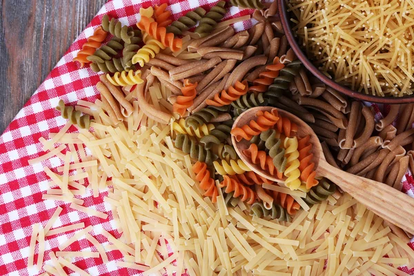 Diferentes tipos de pasta en servilleta sobre fondo de madera —  Fotos de Stock