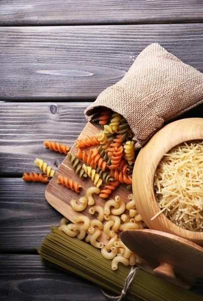 Different types of pasta in containers on wooden background — Stock Photo, Image