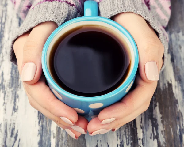Ženské ruce držící šálek kávy na dřevěné pozadí — Stock fotografie