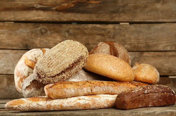 Different fresh bread on old wooden table — Stock Photo, Image