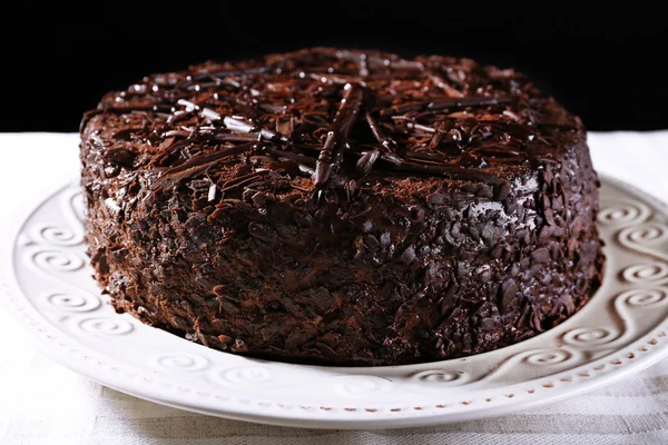 Délicieux gâteau au chocolat dans une assiette sur une table en bois sur fond sombre — Photo
