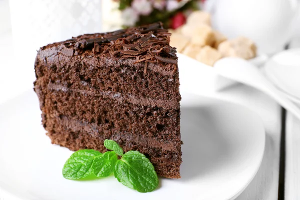 Pedazo de delicioso pastel de chocolate en plato sobre fondo de mesa de madera de color —  Fotos de Stock
