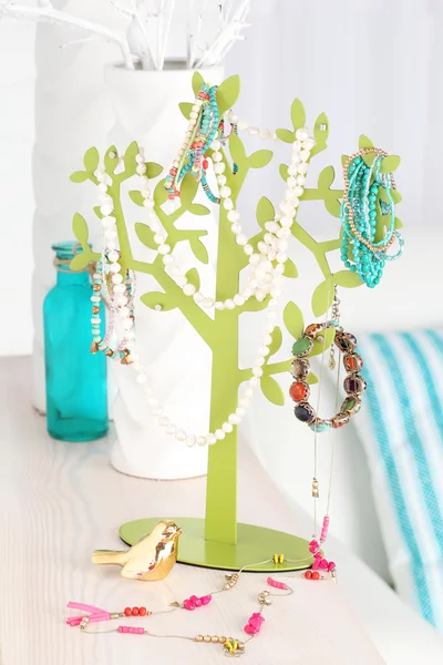 Soporte decorativo con joyas y bijouterie en la mesa en la habitación —  Fotos de Stock