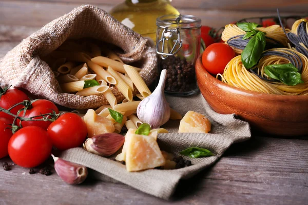 Pasta with cherry tomatoes and other ingredients on wooden table background — Stock Photo, Image