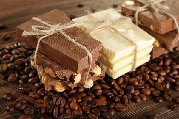 Stack av bundet choklad med kaffebönor på träbord, närbild — Stockfoto
