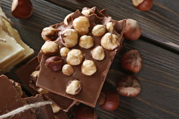 Uppsättning av choklad med hasselnötter på träbord, närbild — Stockfoto
