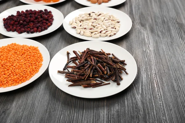 Different products on saucers on wooden table, closeup — Stock Photo, Image