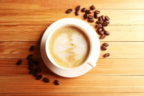 Secangkir kopi latte art dengan biji-bijian di atas meja kayu, pemandangan atas — Stok Foto