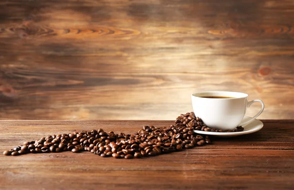 Tazza di caffè con chicchi su sfondo di legno — Foto Stock