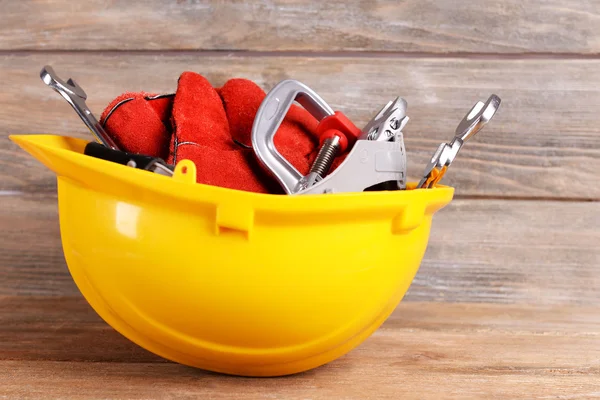 Construction tools in helmet on wooden background — Stock Photo, Image