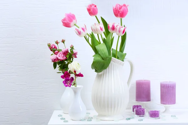 Красивая композиция с различными цветами в вазах на фоне стен — стоковое фото