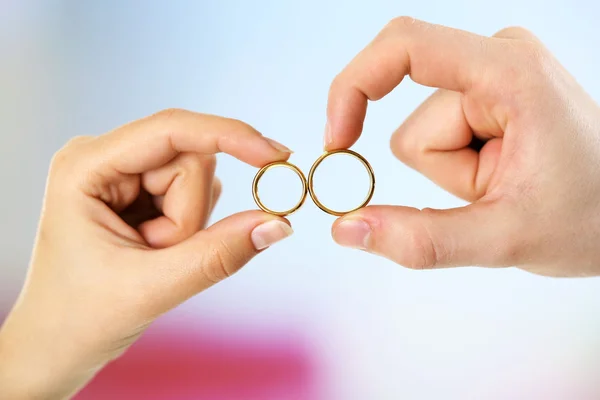 Woman and man holding wedding rings, close-up, on bright background — Stock Photo, Image