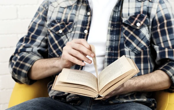 Young man reading book, close-up, on light background — Stock Photo, Image