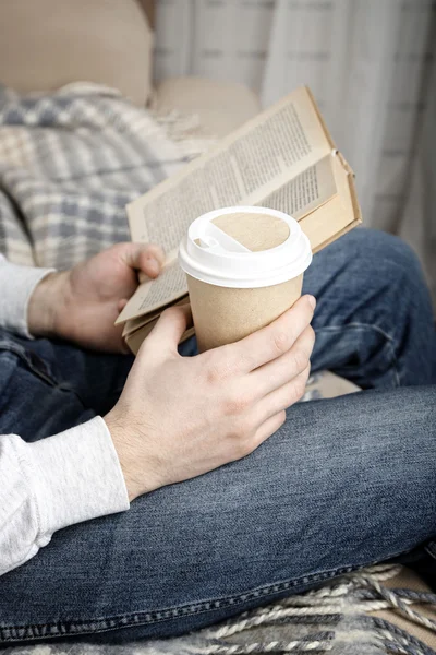 Mladý muž, čtení knihy, close-up, na domácí interiér pozadí — Stock fotografie