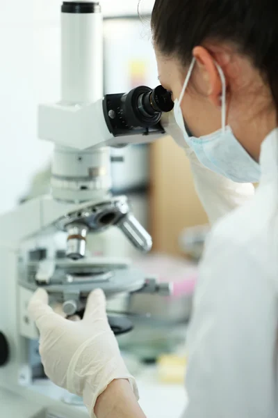 Cientista feminina olhando através de um microscópio em laboratório — Fotografia de Stock