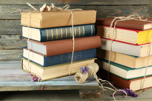 Stacks of books with dry flowers and twine on wooden background — Stock Photo, Image