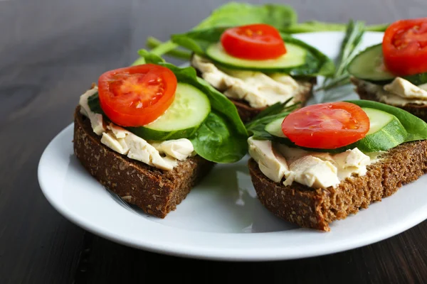 Delicious sandwiches with vegetables and greens on plate close up — Stock Photo, Image
